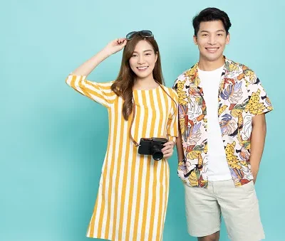 asian couple ready for vacation poses holding a camera and wearing sunglasses isolated on