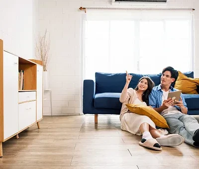 attractive new marriage man and woman sit on the floor together in the living room and point