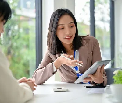 focused asian businesswoman using tablet discussing work and working with her colleague