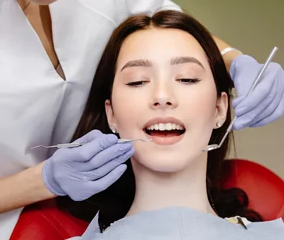 portrait of smiling caucasian lady and cropped dentist hands in blue gloves with tools in