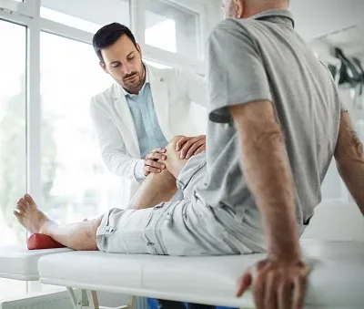 senior man having his knee examined by a doctor