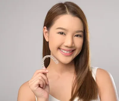 young smiling woman holding invisalign braces over white background studio dental healthcare